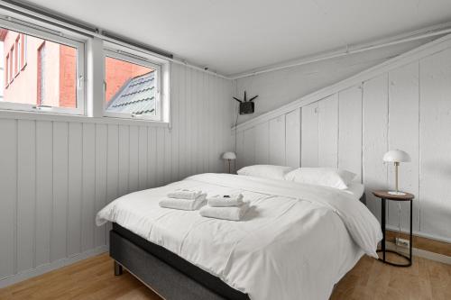 a white bedroom with a large bed with towels on it at Enter Amalie Apartment Hotel in Tromsø