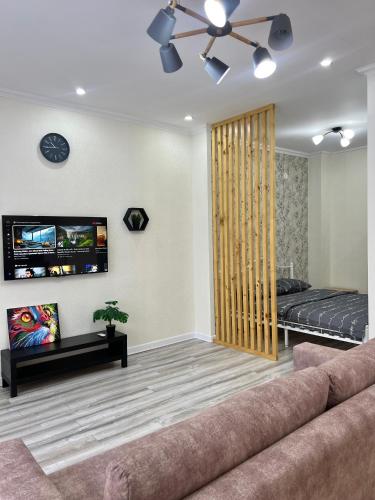 een woonkamer met een bank en een tv bij Уютная однушка в центре города in Atıraw