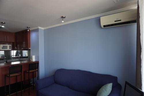 a living room with a blue couch and a kitchen at Pontoni Providencia in Santiago