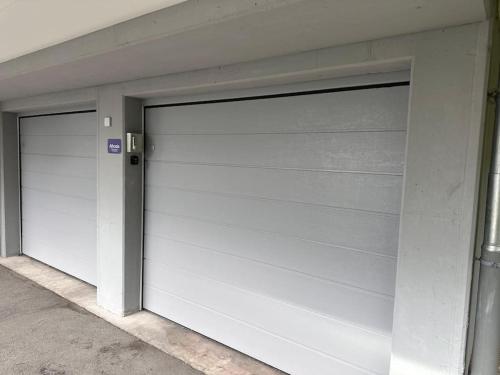 two white garage doors on a building at Ferienwohnung Athosia in Leukerbad