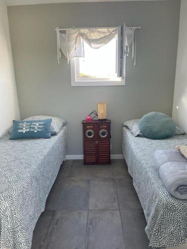 two beds in a room with a window and a table at TI KAZ - Terrasse extérieure - 5mn Plage in Pleubian