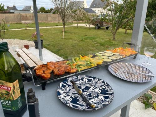 a table with plates of food on a table with wine at TI KAZ - Terrasse extérieure - 5mn Plage in Pleubian