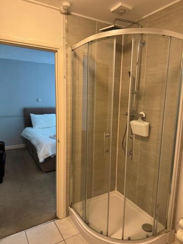 a glass shower in a room with a bed at Cottage Court Hotel in Tenby