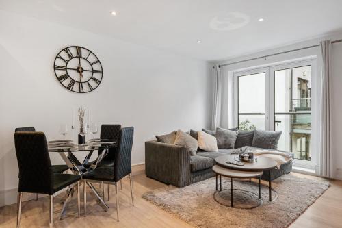 a living room with a couch and a table and a clock at 2 Bedroom Apartment in Kings Cross, London, N1 in London