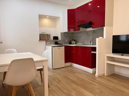 a kitchen with red cabinets and a table and chairs at Kibilù - Bodio near Lake Varese in Lomnago