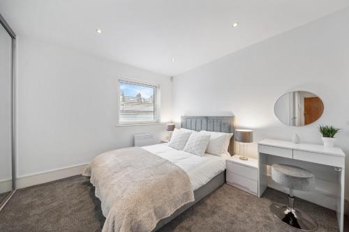 a white bedroom with a bed and a mirror at 2 Bedroom Apartment in Kings Cross, London, N1 in London