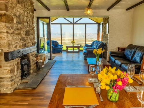 a living room with a table and a stone fireplace at Clyne Farm Centre in The Mumbles