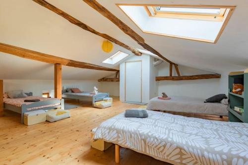 une chambre mansardée avec deux lits et une lucarne dans l'établissement Gîte de la Tour pour 10 personnes à Ganac, à Ganac