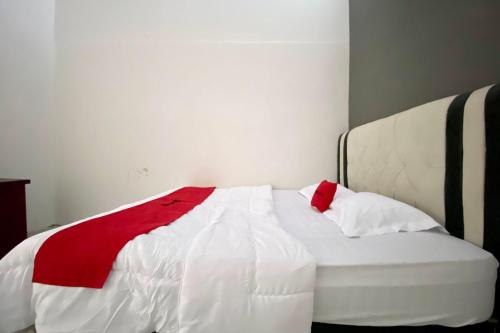 a bed with a red and white blanket on it at RedDoorz Syariah near RSU Sylvani Binjai in Binjai