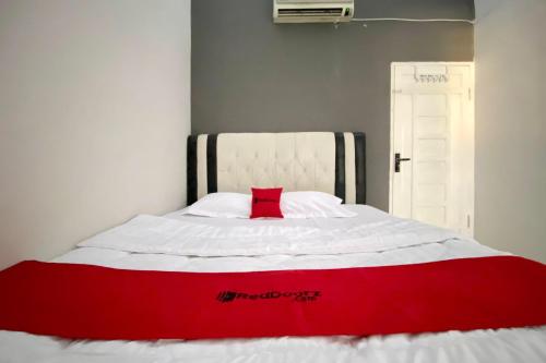 a red and white bed with a red pillow on it at RedDoorz Syariah near RSU Sylvani Binjai in Binjai