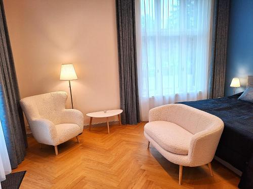 ein Schlafzimmer mit 2 Stühlen, einem Bett und einem Tisch in der Unterkunft Signe Laigu Apartment in Tartu