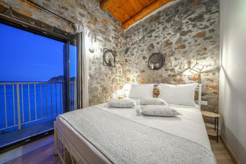 a bedroom with a large bed with a large window at Petra Elounda Suites - Adults Only in Elounda