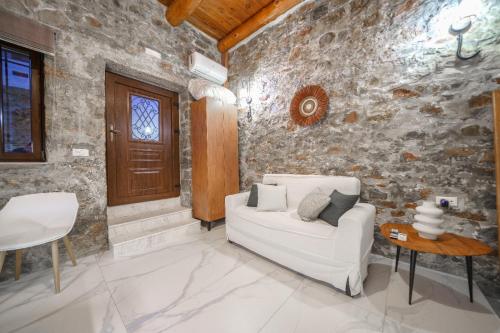 a living room with a white couch and a stone wall at Petra Elounda Suites - Adults Only in Elounda
