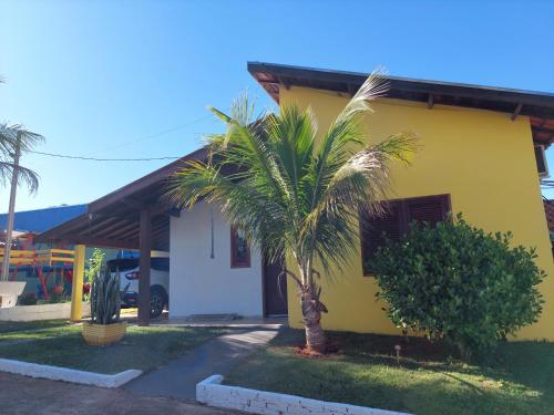 a yellow house with a palm tree in front of it at Temporada Belas Casas in São Pedro