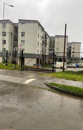 an empty parking lot with a black fence and buildings at Departamento Dichato hasta 7 personas frente a la playa in Dichato