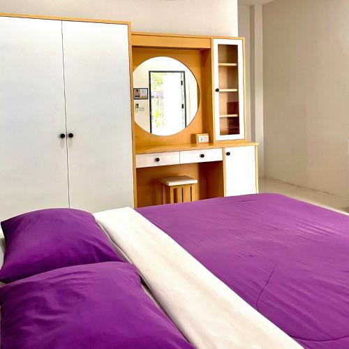 a bedroom with a purple bed and a mirror at บ้านพักสิริ มุกดาหาร (Baan Siri Mukdahan) in Ban Muang Ba