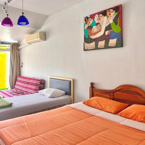 a bedroom with two beds and a painting on the wall at บ้านพักสิริ มุกดาหาร (Baan Siri Mukdahan) in Ban Muang Ba