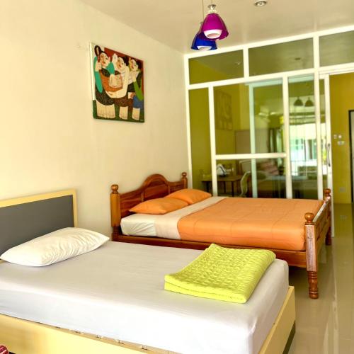 a bedroom with two beds and a painting on the wall at บ้านพักสิริ มุกดาหาร (Baan Siri Mukdahan) in Ban Muang Ba