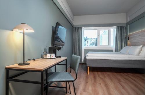 a room with a bed and a desk and a bed and a window at Thon Partner Hotel Kristiansand in Kristiansand
