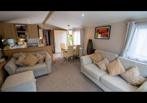 a living room with two couches and a kitchen at 35 Redwood - Beauport Park, Hastings in Hastings