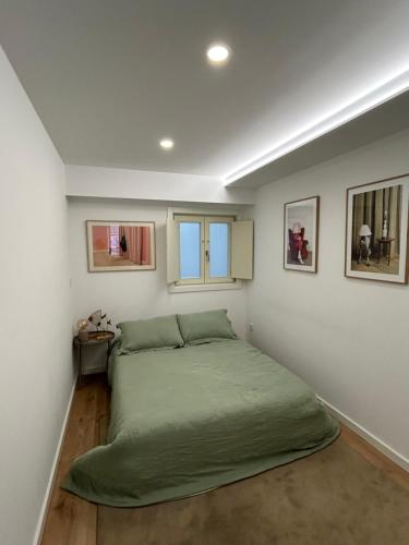 a bedroom with a green bed and two windows at Crato Apartments in Viana do Castelo