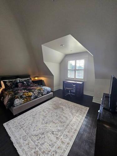 a bedroom with a bed and a desk and a window at IODE Clark House Top Floor Apartment in Fredericton