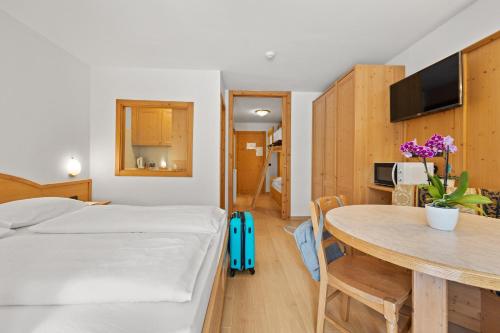 a bedroom with a bed and a table and a room at Aparthotel Princess in Canazei