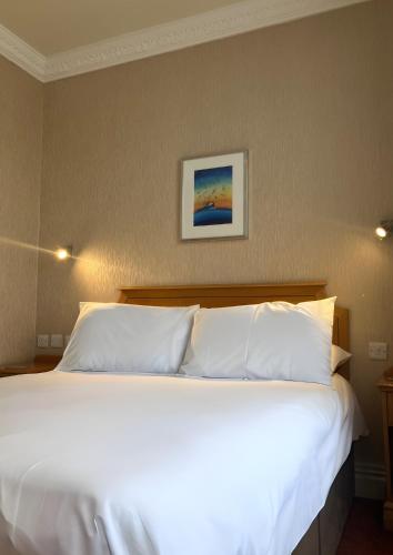 a large bed with white pillows in a bedroom at Welbeck Hotel & Apartments IOM in Douglas