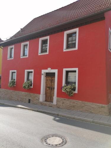 a red building with a red door and windows at Ferienwohnung Annalena in Gößweinstein