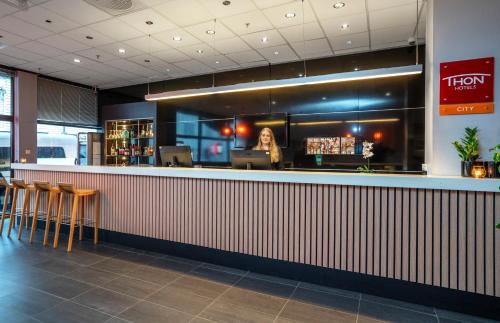 a bar with a woman standing behind the counter at Thon Partner Hotel Kristiansand in Kristiansand
