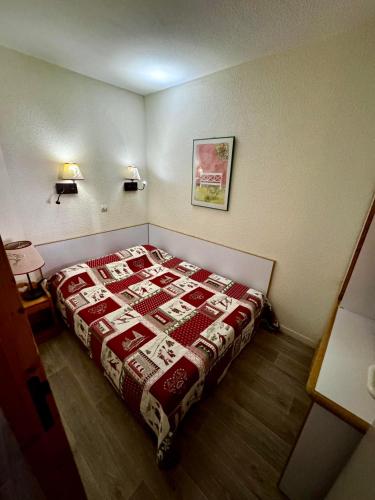 - une chambre dotée d'un lit avec une couverture rouge et blanche dans l'établissement Résidence Licorne BELLE PLAGNE, à La Plagne Tarentaise