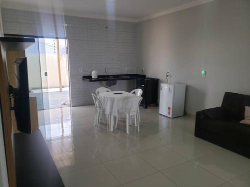 a living room with a table and white chairs at Casa Palmeira in Primavera do Leste