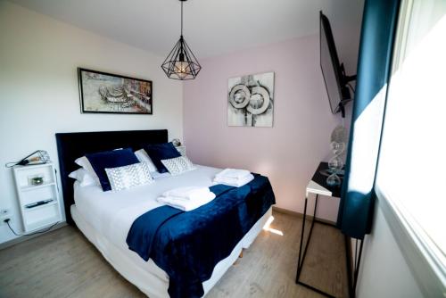 a bedroom with a bed with blue pillows at La Maison de Jade & Spa in La Roche-de-Glun