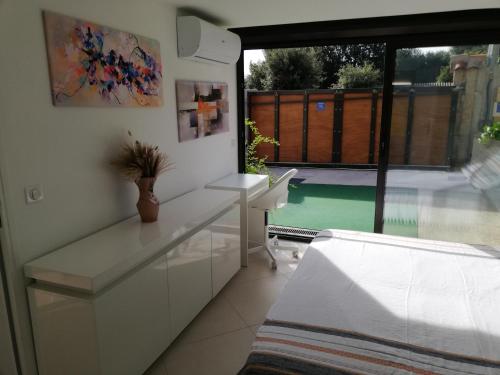 une cuisine blanche avec un bureau et une vue sur la piscine dans l'établissement Appart Sympa au Calme, à Grasse