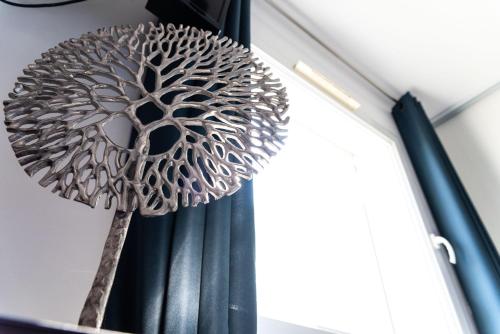 a metal sculpture of a tree on the side of a curtain at La Maison de Jade & Spa in La Roche-de-Glun