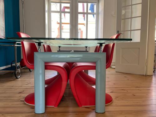 a glass table with red chairs around it at ARTvacanza Neustadt in Neustadt an der Weinstraße