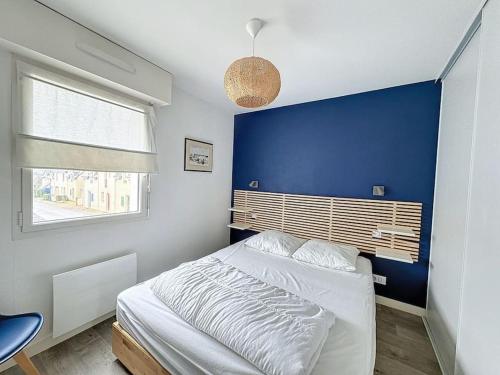 Ce lit se trouve dans une chambre dotée d'un mur bleu. dans l'établissement Appartement tout confort proche plage, à Mesquer