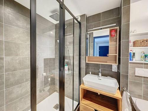 La salle de bains est pourvue d'une douche et d'un lavabo blanc. dans l'établissement Appartement tout confort proche plage, à Mesquer