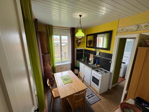 Il comprend une cuisine avec une table en bois et des murs jaunes. dans l'établissement Le Chalet Théodore - Le 5bis, à Wimereux