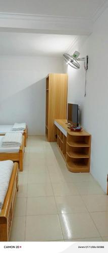 a room with three beds and a desk with a television at Night Market Heart Hotel MC in Mộc Châu