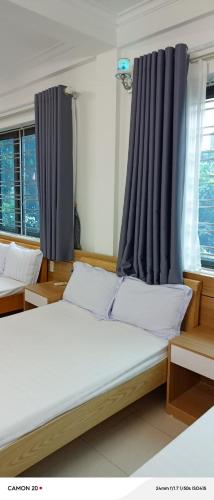 a bedroom with two beds with blue curtains at Night Market Heart Hotel MC in Mộc Châu