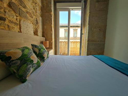 a bedroom with a white bed with a window at Apartamentos Principe in Vigo