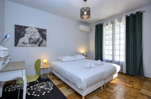 une chambre avec un grand lit blanc et un bureau dans l'établissement La Villa de La Ciotat, à La Ciotat
