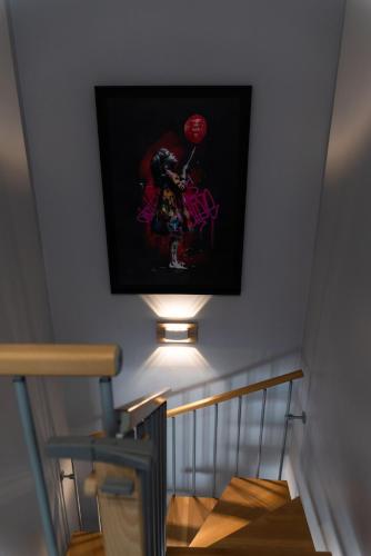 a light on a wall with a picture on a staircase at La Maison de Jade & Spa in La Roche-de-Glun