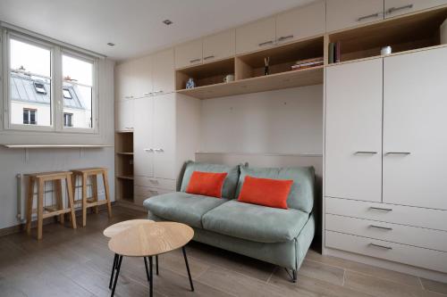 - un salon avec un canapé vert et 2 oreillers orange dans l'établissement Studio Temple - Welkeys, à Paris