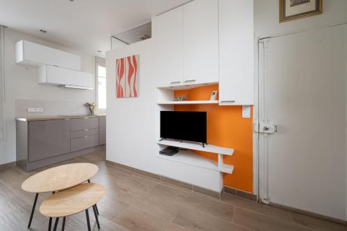 un salon avec une télévision, une table et des chaises dans l'établissement Studio Temple - Welkeys, à Paris