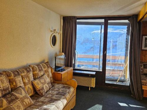 un salon avec un canapé et une grande fenêtre dans l'établissement Charmant 4p, Wi-Fi, animaux admis, Les Menuires - Croisette - FR-1-574-33, aux Menuires
