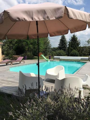 - un parasol et des chaises en face de la piscine dans l'établissement La Grangeneuve la petite maison, à Marclopt