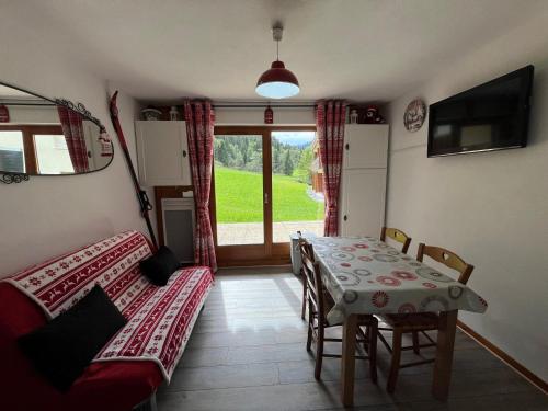 Cette chambre comprend une table, un canapé et une fenêtre. dans l'établissement Appartement cosy avec terrasse, proche télécabine - FR-1-198-88, à Châtel