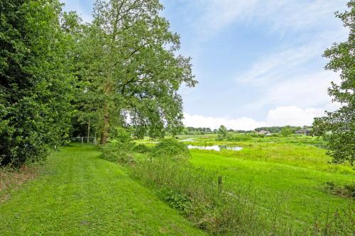 a path through a field with trees and a lake at 't Laankholt in Bornerbroek